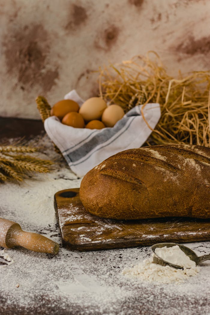 A rustic loaf with fresh ingredients like eggs and wheat on a kitchen counter.