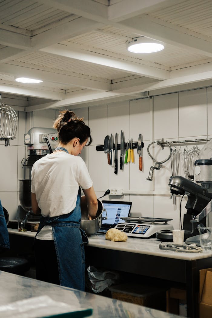 A chef prepares dough in a modern kitchen with baking tools and equipment.