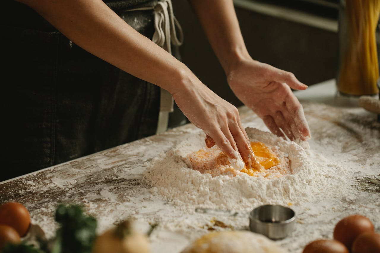 The Art of Drawing Readers In: Your attractive post title goes here Hands kneading dough with eggs and flour for homemade pasta in a kitchen setting.